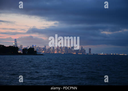 Blick auf die Skyline von Chicago am Horizont leuchtet über dem See in der Abenddämmerung vom Vorgebirge Punkt im Hyde Park Nachbarschaft auf der Südseite. Stockfoto