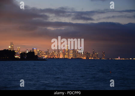 Blick auf die Skyline von Chicago am Horizont leuchtet über dem See in der Abenddämmerung vom Vorgebirge Punkt im Hyde Park Nachbarschaft auf der Südseite. Stockfoto