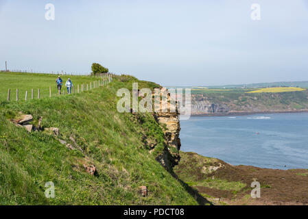 Reifes Paar Wandern auf dem Cleveland Weise Coast Path an einem sonnigen Frühlingstag, Kettleness, Whitby, North Yorkshire, England. Stockfoto