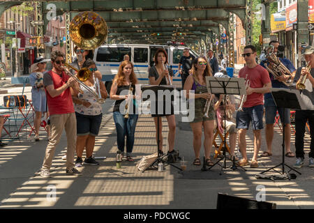 Die 'L-Zug Brass Band" führt unter der Hochbahn auf dem Broadway Bushwick Nachbarschaft von New York während der "Block Party" am Broadway Street Fair am Sonntag, den 5. August 2018. Die Messe, die vom Broadway Merchants Association gesponsert und ist eine Reaktion auf die K2 Epidemie, die der Broadway Flur getätigt hat und bemüht sich, die Menschen zurück zu holen. (Â© Richard B. Levine) Stockfoto