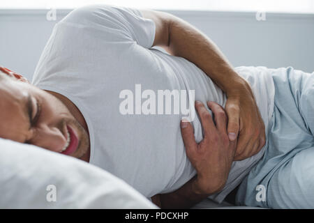 7/8 Schuß des Menschen leiden unter Magenschmerzen im Bett Stockfoto