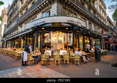 Ein Pariser Café auf einen warmen Sommer Abend, zieht sowohl Einheimische als auch Touristen für Essen im Freien Stockfoto