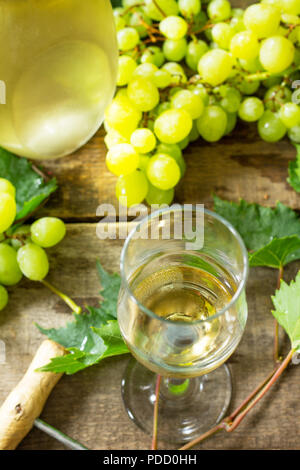 Wein Hintergrund. Weißwein im Glas, Flasche, Trauben auf vintage Hintergrund, Wein Konzept. Stockfoto