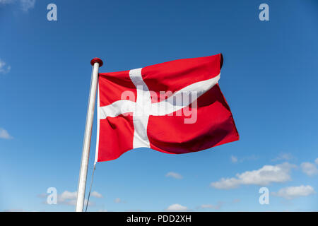Dänische Flagge gegen den blauen Himmel Stockfoto