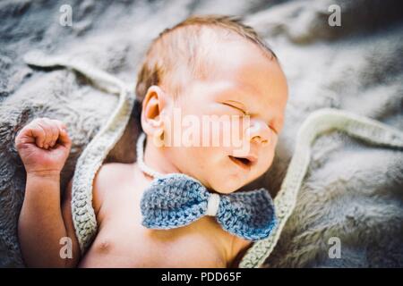 Ein neugeborenes Baby schlafen in Blau und Grau Fliege und Hosen aus Gewirken Stockfoto