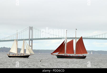 Newport, Rhode Island - Juli 26, 2018: Zwei Segelboot mit roten und weißen Segeln und Newport Bridge von Fort Adams State Park gesehen. Stockfoto