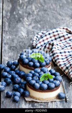 Zwei mini Schokolade Käsekuchen mit frischen Heidelbeeren auf hölzernen Tisch Stockfoto
