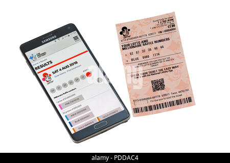 Smart Phone und Lottery Ticket isoliert auf einem weißen Hintergrund die Überprüfung von Ergebnissen Stockfoto