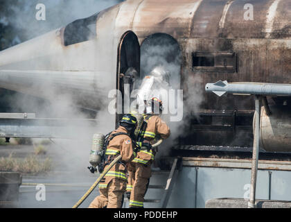 Mitglieder aus dem 18 Bauingenieur Squadron zeigen Mitglieder von Naha Air Base Feuerwehrleute wie ein Flugzeug Feuer während der Gemeinsamen live Fire Training August 7th, 2018 Kadena Air Base, Japan. Die Ausbildung ist das erste unter einem neuen Knowledge Exchange Vereinbarung zwischen JASDF und die US Air Force Feuerwehrmänner. (U.S. Air Force Foto von Airman 1st Class Greg Erwin) Stockfoto