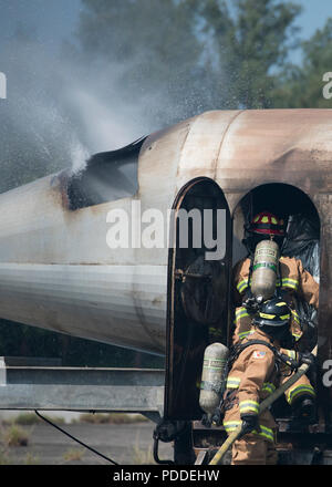 Mitglieder aus dem 18 Bauingenieur Squadron zeigen Mitglieder von Naha Air Base Feuerwehrleute wie ein Flugzeug Feuer während der Gemeinsamen live Fire Training August 7th, 2018 Kadena Air Base, Japan. Die Ausbildung ist das erste unter einem neuen Knowledge Exchange Vereinbarung zwischen JASDF und die US Air Force Feuerwehrmänner. (U.S. Air Force Foto von Airman 1st Class Greg Erwin) Stockfoto