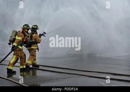 Us-Flieger auf der 51. Bauingenieur Squadron Feuerwehr- und Rettungsdienste Flug zugewiesene Südkoreanischen Feuerwehrmänner bei der Bekämpfung einer simulierten Flugzeugen Brand während einer Übung auf der koreanischen nationalen Universität von Wohlfahrt in Pyeongtaek, Republik Korea, 17. Mai 2018 unterstützen. Die Übung, einer von vielen jährlich statt, war eine groß angelegte, multi-Opfer Szenario, dass eine abgestürzte Flugzeug und mehrere Brände enthalten. Stockfoto