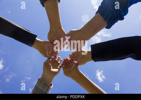 Junge Geschäftsleute die Hände zusammen, Himmel Hintergrund, Stapel von Händen. Einheit und Teamarbeit Konzept. Stockfoto