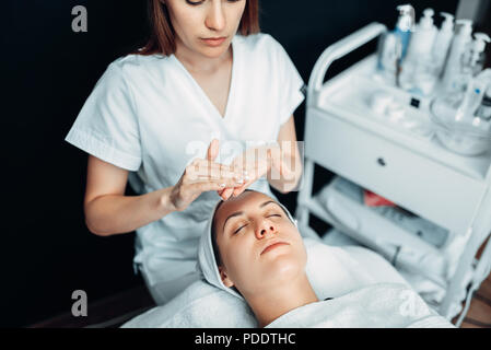 Kosmetikerin Hände mit Creme gegen die beim Patienten Stockfoto