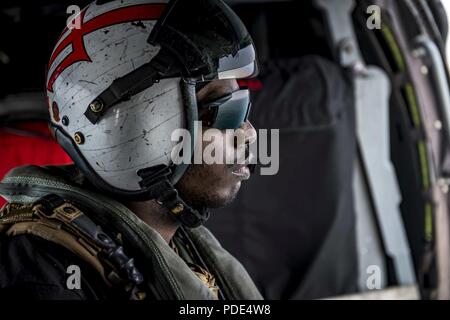 Atlantischer Ozean (12. Mai 2018) Hospital Corpsman 2. Klasse Ryan Jones, von Fayetteville, North Carolina, blickt auf das Wasser aus einem MH-60S Sea Hawk zu Hubschrauber Meer Combat Squadron (HSC) 9. Die Staffel ist an Bord der Flugzeugträger USS George H.W. eingeleitet Bush (CVN 77) und unterwegs in den Atlantischen Ozean Durchführung Carrier Air Wing Übungen mit der Französischen Marine Partnerschaften zu stärken und zu vertiefen, die Interoperabilität zwischen den Seestreitkräften der beiden Länder. Stockfoto