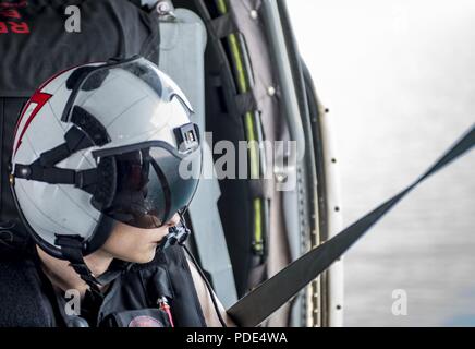 Atlantischer Ozean (12. Mai 2018) Naval Air Crewman 3. Klasse Dereck Christopher, von Decatur, Alabama, blickt auf das Wasser aus einem MH-60S Sea Hawk zu Hubschrauber Meer Combat Squadron (HSC) 9. Die Staffel ist an Bord der Flugzeugträger USS George H.W. eingeleitet Bush (CVN 77) und unterwegs in den Atlantischen Ozean Durchführung Carrier Air Wing Übungen mit der Französischen Marine Partnerschaften zu stärken und zu vertiefen, die Interoperabilität zwischen den Seestreitkräften der beiden Länder. Stockfoto