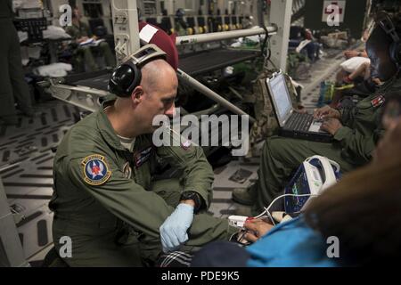 Senior Master Sgt. Brad Markwood, 18 Aeromedical Evacuation Squadron 2 AE Techniker, überprüft die Vitalparameter eines Patienten an Bord einer C-17 Globemaster III von Travis Air Force Base, Calif., 16. Mai 2018, an der Anderson Air Force Base, Guam. AE-Teams bieten und critical care in der Luft für militärische Mitglieder und ihre Familien unterstützen, wie sie Reisen zu folgen - für die medizinische Behandlung Einrichtungen für die medizinische Versorgung oder zu Hause Station zurück. Stockfoto