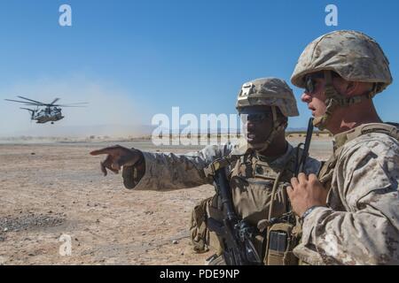 Us Marine Corps Gunnery Sgt. Martin Beatty, Links, und Cpl. Logan Roberts direkter die Reihenfolge der Truppen in das Flugzeug in eine An- und Abreise Airfield control Group (A/DACG) während ITX 3-18 auf der Marine Corps Air Ground Combat Center, Twentynine Palms, Calif., 18. Mai 2018. Ein A/DACG ist die auf der Ladung oder aus Last von persönlichen und Fracht auf ein Flugzeug zur Unterstützung der Missionen in einem Feld. Der Zweck von ITX 3-18 ist eine anspruchsvolle, realistische Umgebung, produziert combat ready"-Kräfte, die als integrierte Marine Air Ground Task Force zu erstellen. Stockfoto