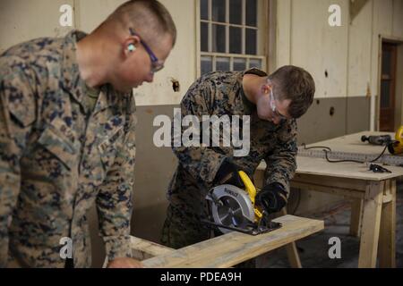 Us Marine Lance Cpl. Mitchell R. Neimann (rechts), schwere Ausrüstung Fahrer mit dem Ingenieur Unternehmen C, 6 Techniker, 4. Marine Logistik Gruppe, nutzt eine Kreissäge zu schneiden einem holzbrett als US Marine Cpl. Evan A. Olsen (links), Kfz-Mechaniker mit ECC, 6. ESB, 4. MLG, hält das Holz an Ort und Stelle auf einer Baustelle während der Übung rote Dolch am Fort Indiantown Gap, Pa, 19. Mai 2018. Übung rote Dolch ist eine bilaterale Übung, die Marines die Möglichkeit, Taktiken, Techniken und Verfahren sowie Aufbau von Arbeitsbeziehungen Stockfoto