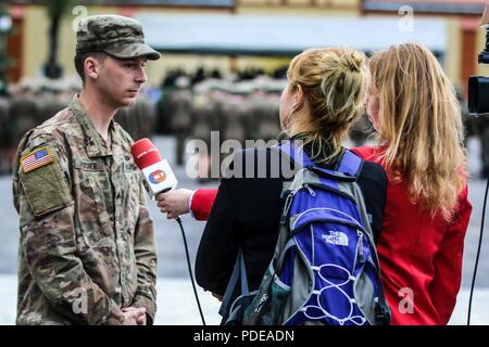 Sgt. Patrick Fischer (links), ein Milwaukee, Wisconsin Eingeborener und Infanteristen mit 1St Squadron, 2.Kavallerie Regiments, ist von Justyna Drozd (rechts), ein Reporter mit Ketrzyn Kabel Fernsehen interviewt, während einer Veranstaltung zum Jahrestag der polnischen Grenze Wache mit Battle Group Polen in Ketrzyn, Polen am 18.Mai 2018 feiern. Battle Group Polen ist ein einzigartiges, multinationale Koalition von USA, Großbritannien, Kroatischen und rumänischen Soldaten, die mit der polnischen 15 mechanisierte Brigade als Abschreckung Kraft zur Unterstützung des NATO-Enhanced vorwärts Präsenz dienen. Stockfoto