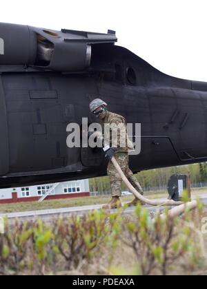 Alaska Army National Guard Pvt. Marvin Caparas, die Petroleumversorgung Spezialist Soldat mit E Unternehmen, 1.BATAILLON, 207 Aviation Regiment, tankt ein 1-207 th Aviation UH-60 Black Hawk Hubschrauber während vorwärts Bereich Rüstung und tanken Point Operations 19. Mai 2018, am Bryant Army Airfield, Joint Base Elmendorf-Richardson, Alaska. Die FAARP unterstützt die schnelle Auftanken von 1-207 th Aviation UH-60 s Während der wildfire Schulung. Stockfoto