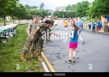 Ein US-Marine bietet Wasser zu einem Teilnehmer des 11. jährlichen Marine Corps historischen (MCHH) laufen in Fredericksburg, Virginia, 20. Mai 2018. Die MCHH lockt über 8.000 Teilnehmer und beinhaltet die Devil Dog Double und Marine Corps Semper 5ive Rennen. Stockfoto
