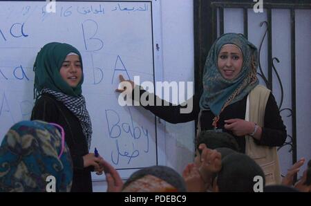 Ein junger Student zeigt ihre Lehrer und Klasse wie das Wort 'Baby zu schreiben "das englische Alphabet an Der neue Horizonte für Ain Issa Schule, in Ain Ivss, Syrien, 16. Mai 2018. Vor der Niederlage der ISIS, Schulen in der Region wurden weitgehend evakuiert und für fast fünf Jahre geschlossen. Neue Horizonte für Ain Issa eröffnet mit der Unterstützung des US-Außenministeriums im vergangenen Jahr und nun bietet Ausbildung für eine Reihe von Bedürfnissen, einschließlich Sonderpädagogik, psychosoziale Unterstützung, Gebärdensprache und Alphabetisierung. Die Wiedereingliederung der Kinder in die Gesellschaft durch Erziehung und Sozialisierung ist ein weiterer Schritt in Richtung Norma Stockfoto