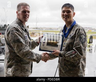 Us Air Force Colonel Mathew Powell, Kommandant der 3. Wartung Gruppe, präsentiert Master Sgt. Samuel Alonzo mit den Waffen, Manager des Quartals Award nach dem Flügel Waffen laden Crew 1. Quartal Wettbewerb Mai 18, 2018, Joint Base Elmendorf-Richardson, Alaska. Die vierteljährlichen Wettbewerb besteht aus zwei AMU Waffen - Abschnitt teams Kopf an Kopf für Zeit und Genauigkeit. Stockfoto