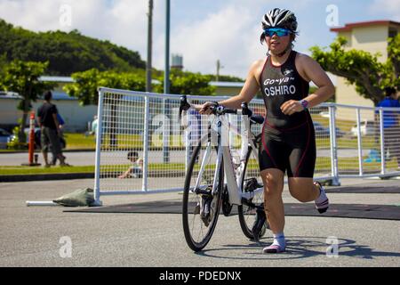 CAMP KINSER, Okinawa, Japan - ein Teilnehmer läuft in die Wechselzone nach Abschluss der Radstrecke während der kinser Triathlon 18. Mai an Bord Camp Kinser, Okinawa, Japan. Insgesamt 96 Teilnehmer aus den lokalen und US-Gemeinschaften in diesem Jahr an der Veranstaltung teilgenommen. Die offene Triathlon bestand aus einem 5-km-Lauf, durch eine 15-km-Radstrecke gefolgt, und mit einem 400-Meter schwimmen. Stockfoto