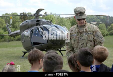 Chief Warrant Officer 3 Joval Eblen, ein Hubschrauberpilot zu den Joint Multinational Readiness Center zugeordnet, zeigt die Funktionsfähigkeit der UH-72A Lakota Light Utility Helicopter Kinder aus der Grundschule Hohenfels während der Schatten Tage Schule in Hohenfels, Hohenfels, Deutschland, 15. Mai 2018. Job Shadow Days sind eine jährliche 3-tägige Veranstaltung, wo Schüler aus der Volksschule und Hohenfels Hohenfels Mitte/High School verschiedene militärische berufliche Fähigkeiten, die an HTA vorhanden sind, dargestellt werden. Stockfoto