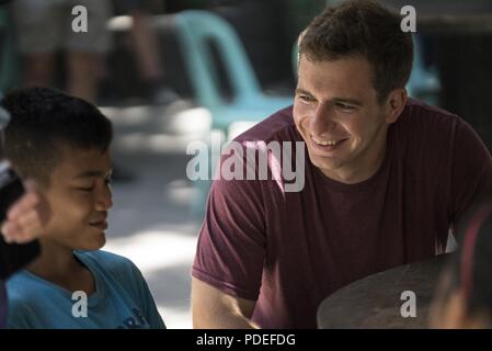 Ein US Air Force 17 Special Operations Squadron Mitglied kommuniziert mit einer philippinischen Jugendlichen aus Subic Bay's Kinderheim während einer Community Relations Veranstaltung Mai 12, 2018, in Subic Bay, Philippinen. Die militärische Mitglieder gezeigt, Aufwertung der lokalen Gemeinschaft während Balikatan 2018 mit einem Tag der Aktivitäten, die Eröffnungsfeier, musikalische Darbietungen, Mittagessen und Sport Spiele enthalten. Stockfoto
