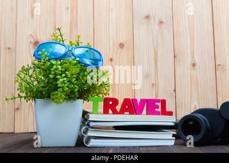 Reisen Buchstaben text und Notebook Papier, Wecker und wenig Deko Baum in weiße Vase auf hölzernen Hintergrund, Reise Urlaub Konzept Idee. Stockfoto