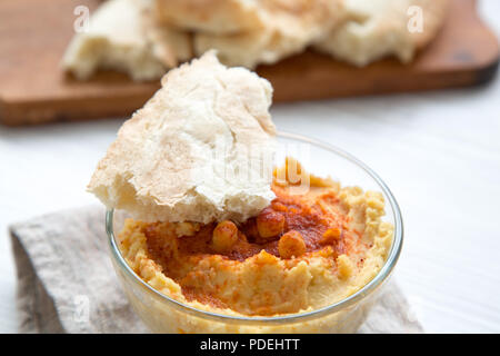 Hummus in Schüssel mit gerösteten Kichererbsen, Paprika, Olivenöl und Fladenbrot, Nahaufnahme. Stockfoto