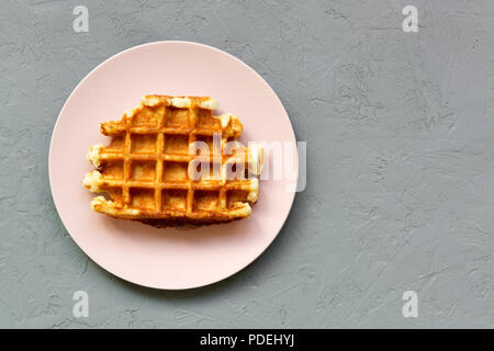 Traditionelle belgische Waffel auf Rosa die Platte über der Betonoberfläche, flach. Von oben und Overhead. Kopieren Sie Platz. Stockfoto