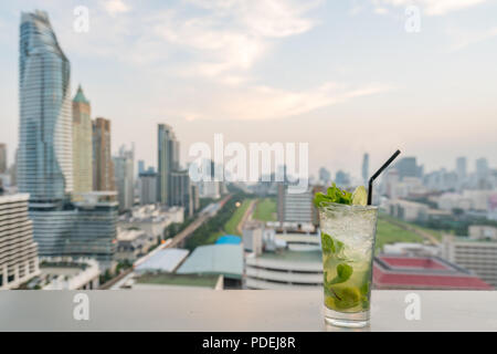 Mojito cocktail am Tisch in der Bar auf der Dachterrasse mit Blick auf die Stadt Bangkok in Bangkok Thailand Punkt. Schöne Dachterrasse mit Bar in Bangkok. Stockfoto