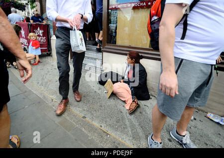 Obdachlose Frau durch die Tür eines Coffee shop Betteln als Menschen gehen vorbei. Kleines Mädchen auf der Suche nach ihr. Whitehall, London, England, UK. Stockfoto