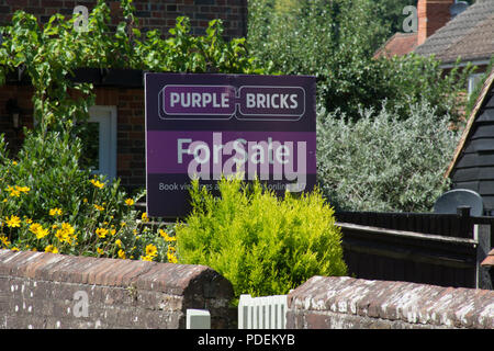 Lila Ziegel der Immobilienmakler für Verkauf Zeichen außerhalb eines Hauses in Surrey, Großbritannien Stockfoto