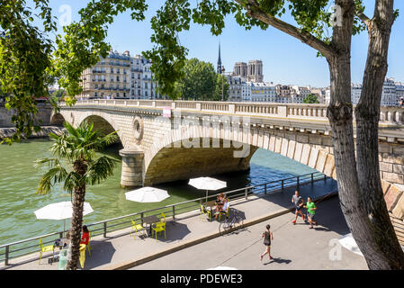 Leute gehen Joggen oder ein Getränk an den Ufern der Seine, während am Pariser Sommerstrand Sommer Event mit Notre-Dame de Paris Kathedrale im Hintergrund. Stockfoto