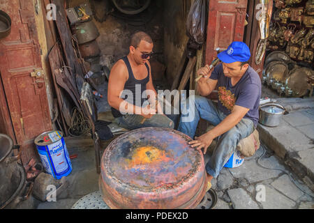 Fez, Marokko - Mai, 11 2013: Junge marokkanische Männer schmieden eine kupferne Topf in einem Souk in Fes Medina, Marokko Stockfoto