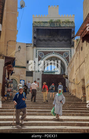 Fes, Marokko - 11. Mai 2013: Einheimische und Touristen zu Fuß in der Medina von Fes, auf der Treppe zu einem reich verzierten Tor mit Mosaik gestaltet Stockfoto