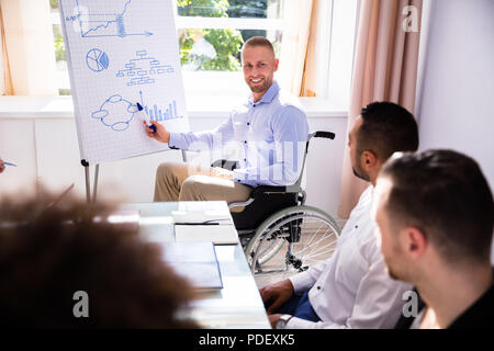 Behinderte junge Geschäftsmann eine Präsentation halten zu seinem Kollegen Stockfoto