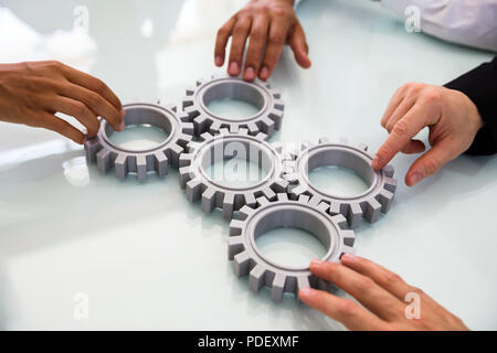 Close-up's Business Menschen Hand verbinden Zahnräder auf Schreibtisch Stockfoto