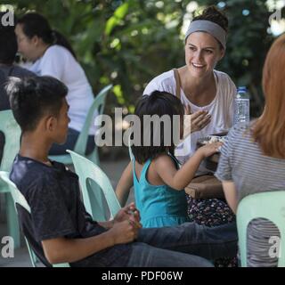 Ein US Air Force 17 Special Operations Squadron Mitglied kommuniziert mit einer philippinischen Jugendlichen aus Subic Bay's Kinderheim während einer Community Relations Veranstaltung Mai 12, 2018, in Subic Bay, Philippinen. Die militärische Mitglieder gezeigt, Aufwertung der lokalen Gemeinschaft während Balikatan 2018 mit einem Tag der Aktivitäten, die Eröffnungsfeier, musikalische Darbietungen, Mittagessen und Sport Spiele enthalten. Stockfoto