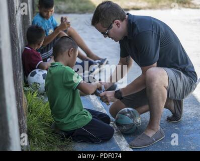 Ein US Air Force 353 Special Operations Mitglied der Gruppe engagiert sich mit einem philippinischen Jugendlichen aus Subic Bay's Kinderheim während einer Community Relations Veranstaltung Mai 12, 2018, in Subic Bay, Philippinen. Die militärische Mitglieder gezeigt, Aufwertung der lokalen Gemeinschaft während Balikatan 2018 mit einem Tag der Aktivitäten, die Eröffnungsfeier, musikalische Darbietungen, Mittagessen und Sport Spiele enthalten. Stockfoto