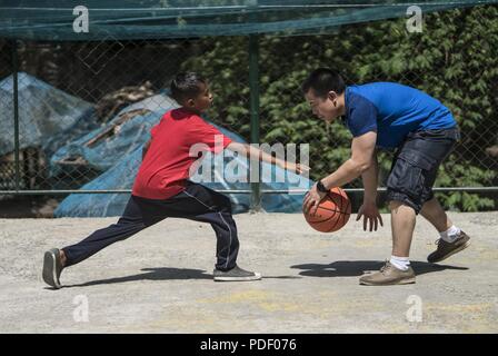 Ein US Air Force 17 Special Operations Squadron Mitglied spielt Sport mit philippinischen Jugendlichen aus Subic Bay's Kinderheim während einer Community Relations Veranstaltung Mai 12, 2018, in Subic Bay, Philippinen. Die militärische Mitglieder gezeigt, Aufwertung der lokalen Gemeinschaft während Balikatan 2018 mit einem Tag der Aktivitäten, die Eröffnungsfeier, musikalische Darbietungen, Mittagessen und Sport Spiele enthalten. Stockfoto