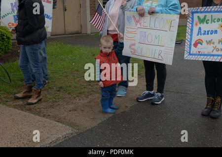 Ein Junge Wellen eine kleine amerikanische Flagge sein älterer Bruder nach Hause von "Deployment willkommen zu heißen", 19. Mai 2018, während der Tag der Bereitstellung bei Bradley Air National Guard Base in East Granby, Anschl. Kinder zwischen Kindergarten und 8 Grad durch eine simulierte Bereitstellung in der Flight-line, die durch ein homecoming Zeremonie gefolgt war. Stockfoto