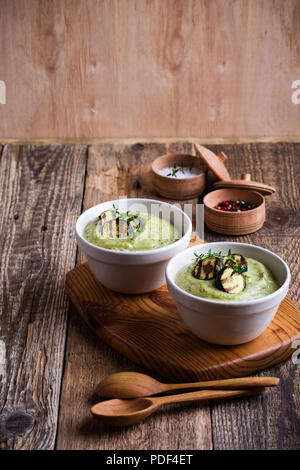 Gesunde zucchini Creme Suppe in Keramik Schalen auf hölzernen Tisch Stockfoto