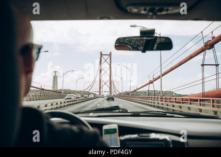 Blick aus dem Auto. Der Fahrer fährt über die Brücke, 25. April in Lissabon in Portugal. Anreise mit dem Auto oder eine Fahrt mit einem persönlichen täglichen Geschäft. Stockfoto