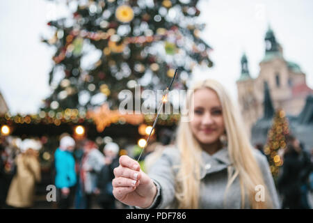 Das Mädchen ist mit einem bengalischen Feuer in der Hand während der Feier von Weihnachten. Altstadt und der Weihnachtsbaum in Prag in der Tschechischen Republik im Hintergrund. Stockfoto