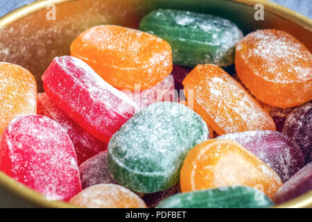 Ein Glas mit hellen Süßigkeit. Die Freude der Kinder, eine Menge Süßigkeiten. Candy Farben sortiert. Karamell in Puderzucker. Farbige Süßigkeiten. Rot Gelb Grün Orange. Stockfoto