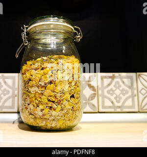 Müsli mit Nüssen und Trockenfrüchten in einem Glas. Auf dem Küchentisch Stockfoto